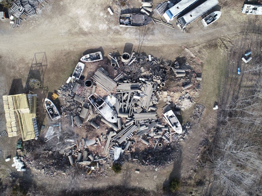 Aerial view straight down on a rubble pile of concrete pipe, slabs and lumber, with boats around its edge