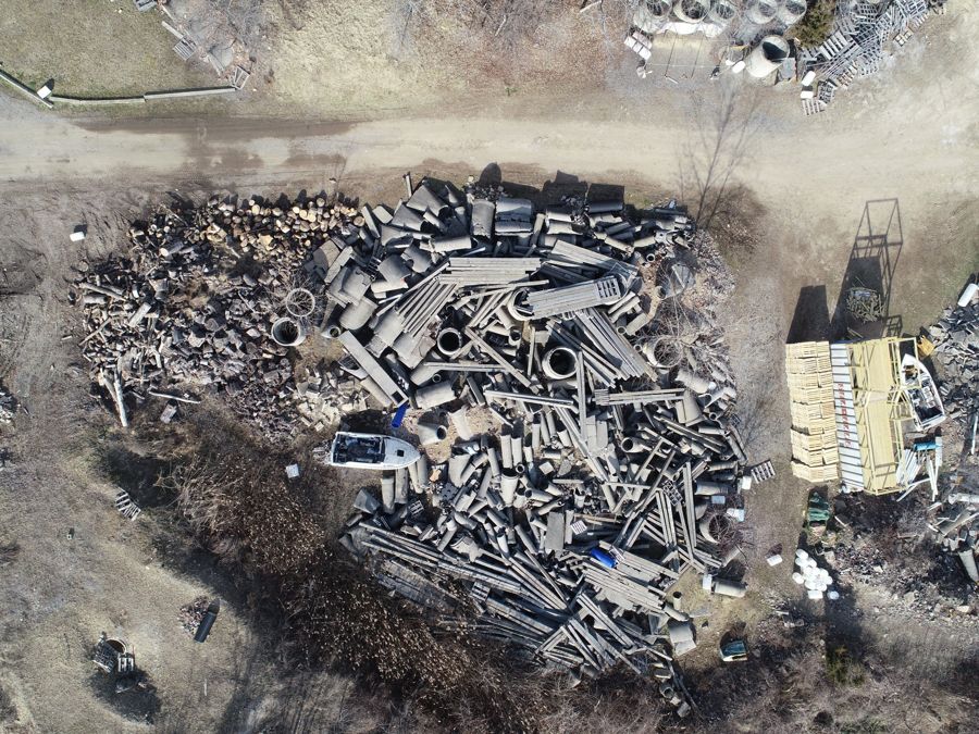 Aerial view straight down on a large rubble pile of concrete pipe and lumber with a pile of logs on one side